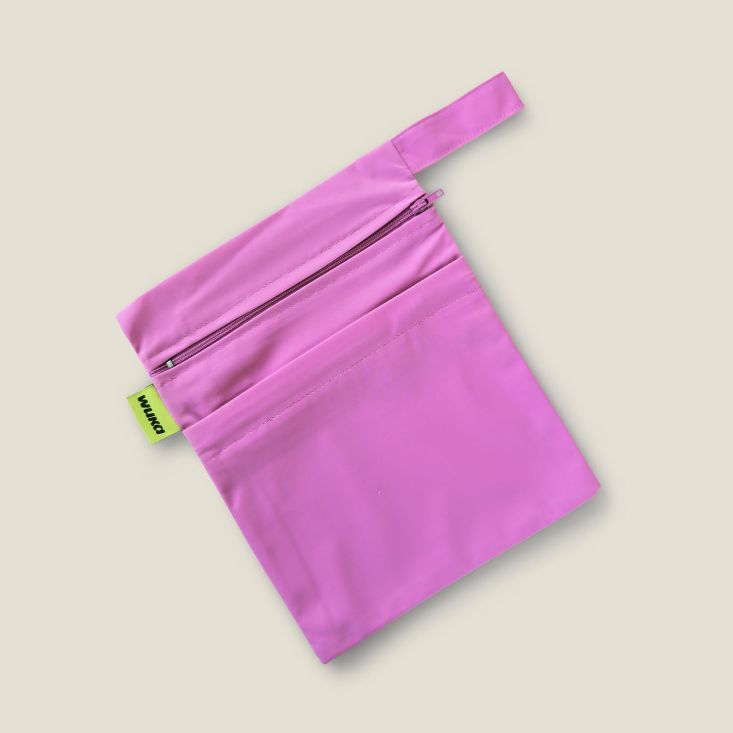 Flat lay of WUKA pink water-resistant two-pocket changing bag with secure zip and discreet design