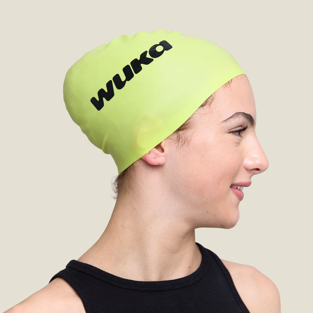 Side profile of a teen in the WUKA lime punch swim cap with bold black WUKA logo.