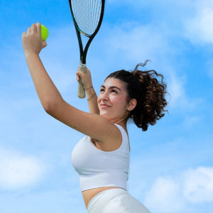 Teen girl playing tennis outdoors wearing WUKA period underwear, showing freedom to stay active during her period